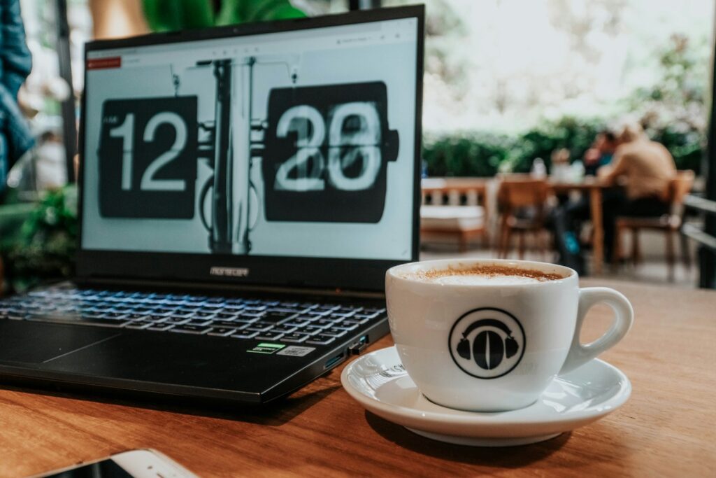 black and silver laptop computer beside white ceramic mug with saucer on brown wooden table