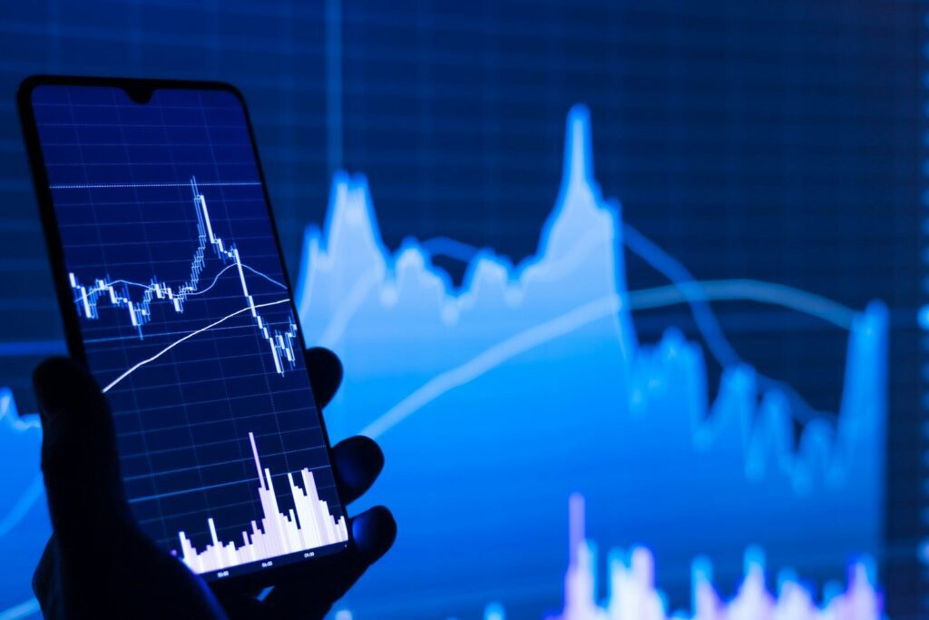 a person holding a cell phone in front of a stock chart, Ratios de valorisations