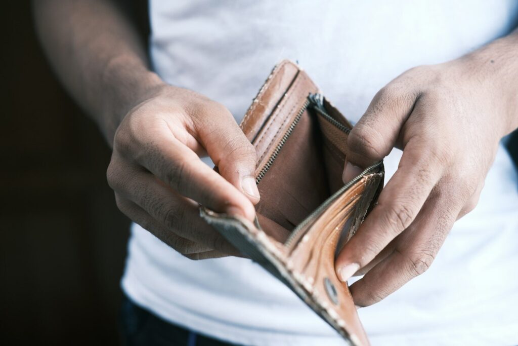 person holding brown leather bifold wallet, éviter de tout dépenser à la fin du mois
