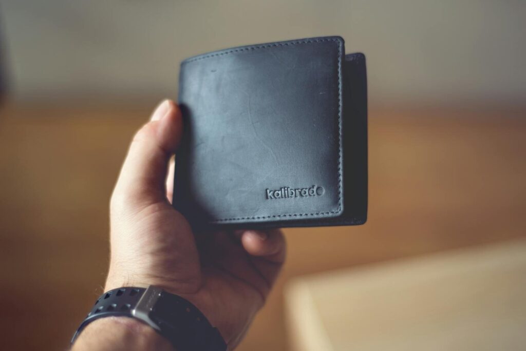Close-up of a stylish black leather wallet held by a person, showcasing design. Les 3 types d'épargne