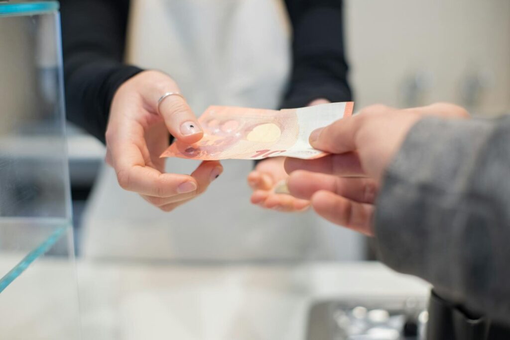Close interaction of hands exchanging cash in a café setting. Business transaction detail. Pourquoi les États s’endettent