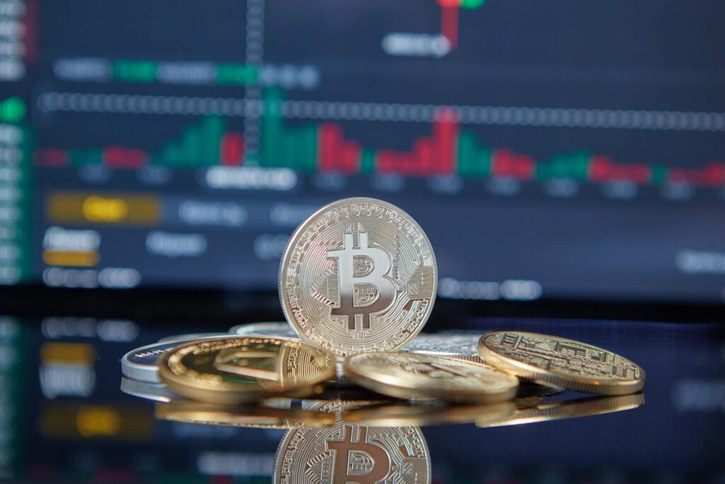 Bitcoin cryptocurrency coins in focus with a blurred stock market chart in the background, representing investment and finance. destruction créatrice