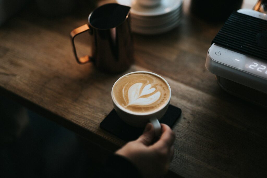 a person holding a cup of coffee on top of a wooden table, Comprendre le système monétaire