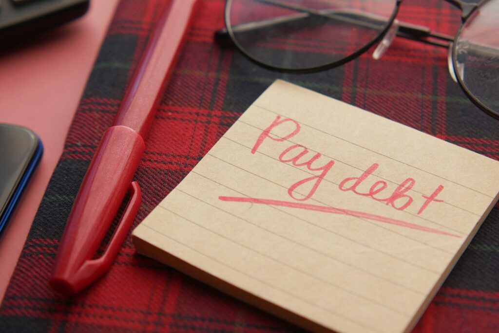 a note that says pay debt next to a pen and glasses, Pourquoi les États s’endettent